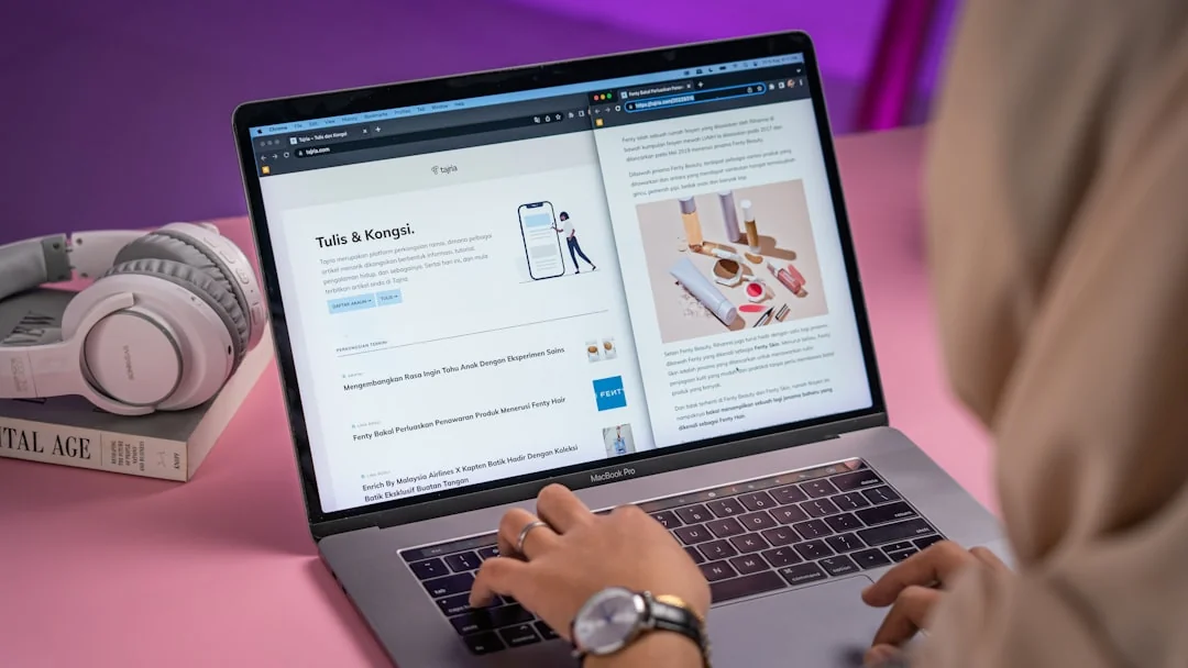 Hand holding smartphone with email app open, surrounded by books and laptop.